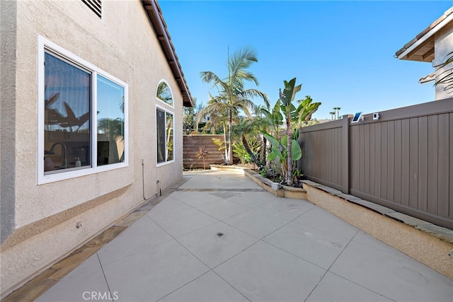 view of property exterior with stucco siding, a patio area, and a fenced backyard