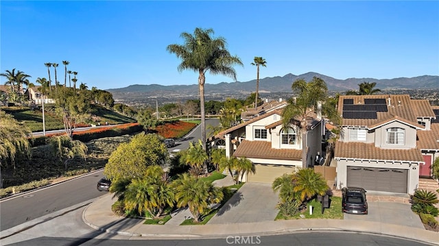 exterior space featuring concrete driveway, a mountain view, a tiled roof, and a garage