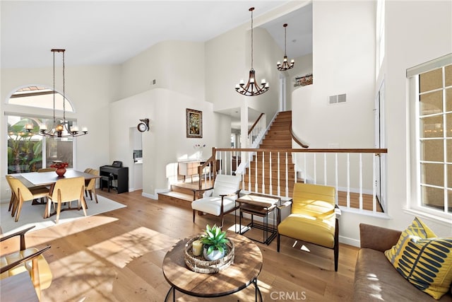 living room featuring hardwood / wood-style flooring, visible vents, an inviting chandelier, and stairs