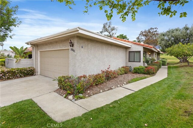 1061 Pebble Beach Dr, Upland, CA 91784 - view of property exterior featuring a garage, stucco siding, driveway, and a lawn