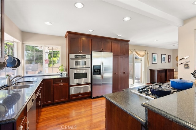 kitchen featuring recessed lighting, light wood finished floors, stainless steel appliances, a sink, and a warming drawer