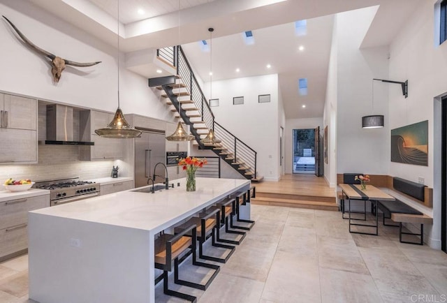132628 Rainbow Ridge Ln, Encinitas, CA 92024 - kitchen with modern cabinets, a towering ceiling, wall chimney exhaust hood, a sink, and light countertops
