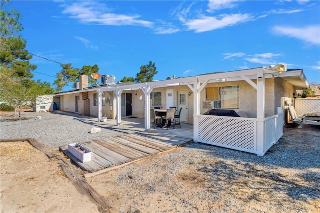 back of property with a patio area, stucco siding, and a chimney