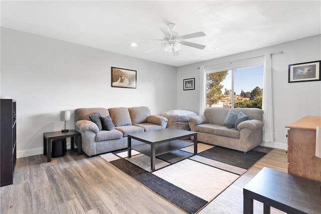 living room featuring light wood-type flooring, a ceiling fan, baseboards, and recessed lighting