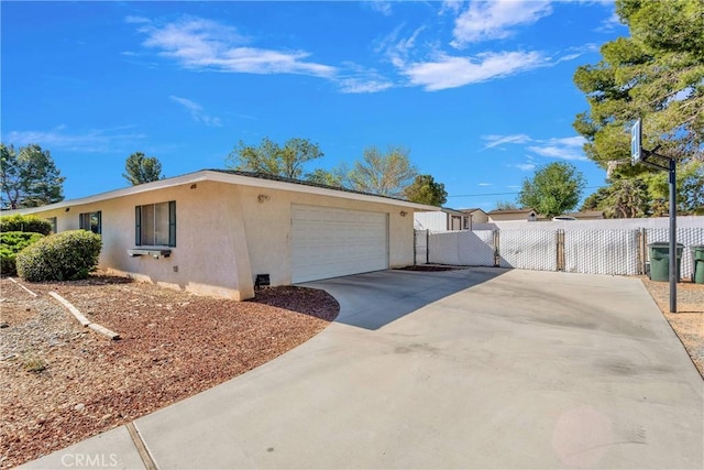 view of property exterior with a garage, stucco siding, driveway, and fence