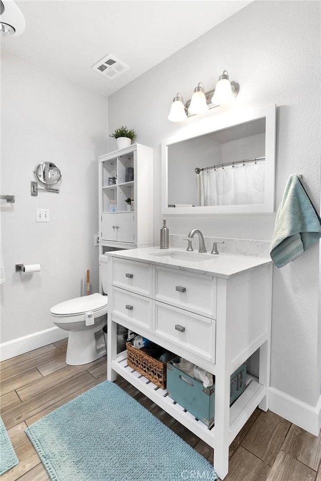 full bathroom with visible vents, baseboards, wood finished floors, and toilet