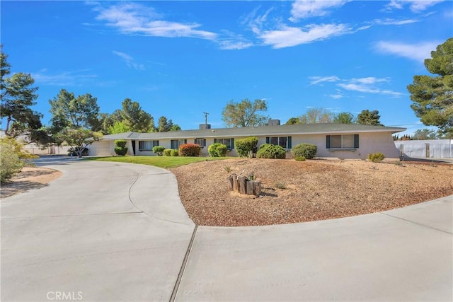 ranch-style home featuring curved driveway and stucco siding