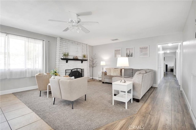 living room with a ceiling fan, baseboards, visible vents, and a fireplace