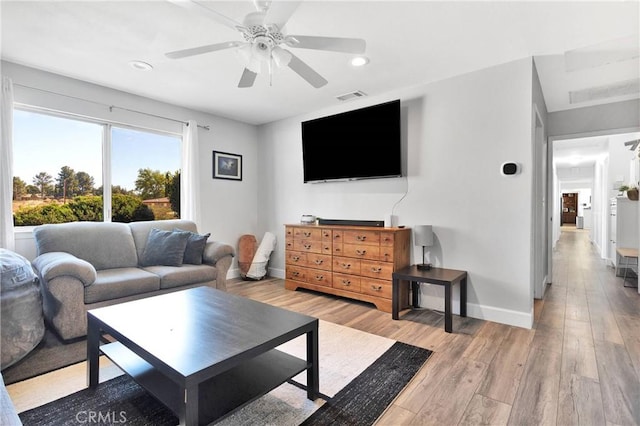living area featuring visible vents, a ceiling fan, light wood-style floors, and baseboards