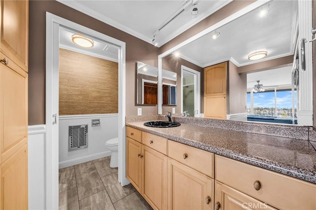 bathroom with toilet, ornamental molding, vanity, and a wainscoted wall
