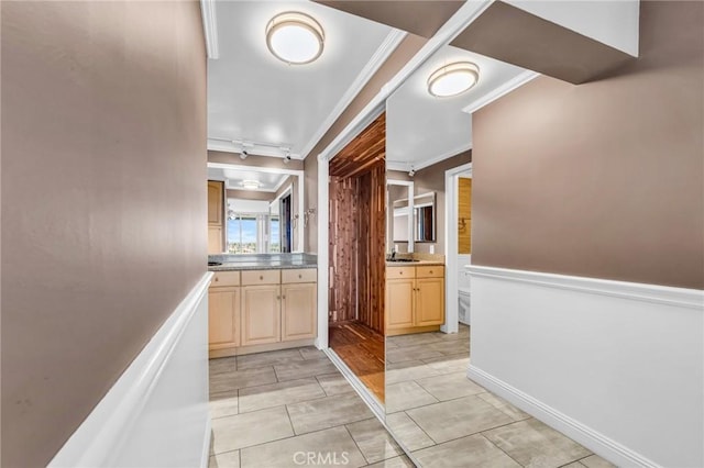 hallway featuring wainscoting, crown molding, and a sink