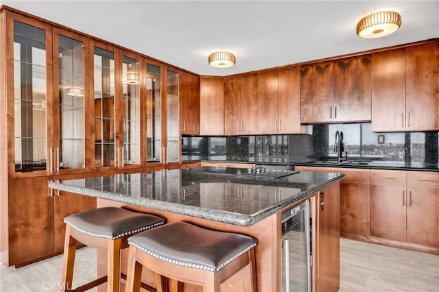 kitchen featuring backsplash, beverage cooler, a sink, and black electric cooktop