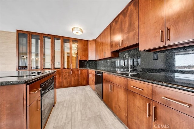 kitchen with tasteful backsplash, dark stone countertops, a sink, brown cabinetry, and black appliances
