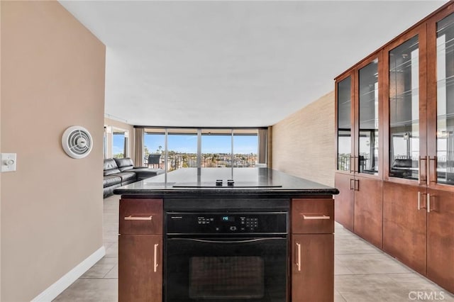 kitchen featuring dark countertops, glass insert cabinets, a kitchen island, and black appliances