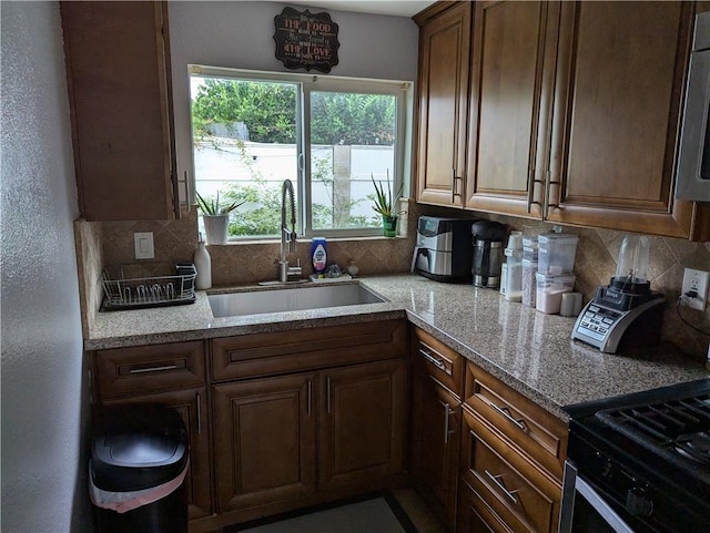 kitchen with decorative backsplash, a sink, stainless steel microwave, and range with gas cooktop