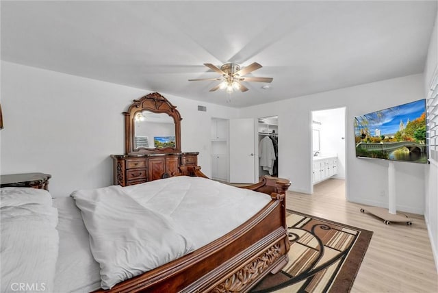 bedroom featuring a closet, a spacious closet, ceiling fan, light wood finished floors, and ensuite bath