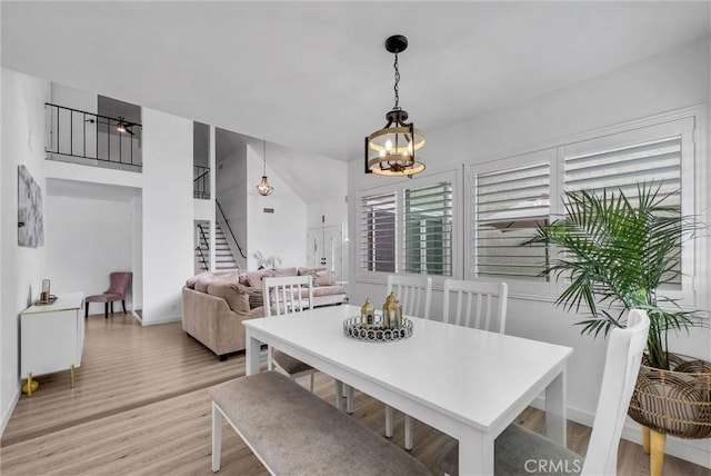 dining area featuring baseboards, a chandelier, stairs, and light wood-style floors