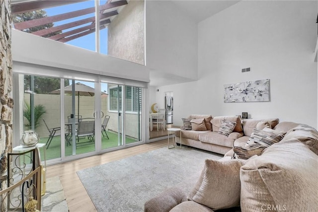 living room with wood finished floors, a high ceiling, a wealth of natural light, and visible vents