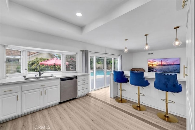 kitchen featuring stainless steel dishwasher, a sink, light wood-style flooring, light countertops, and white cabinets