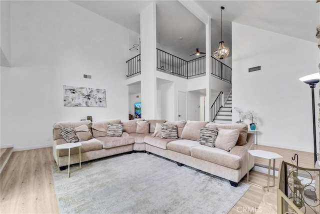 living area with wood finished floors, visible vents, and high vaulted ceiling