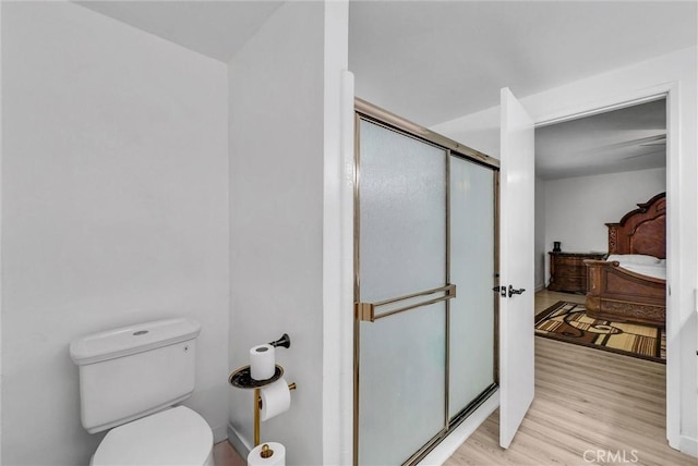 bathroom with toilet, wood finished floors, ensuite bath, and a stall shower