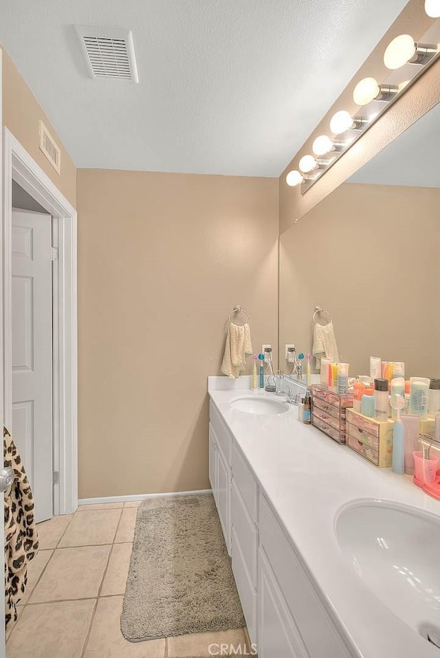 bathroom with tile patterned floors, double vanity, baseboards, and a textured ceiling