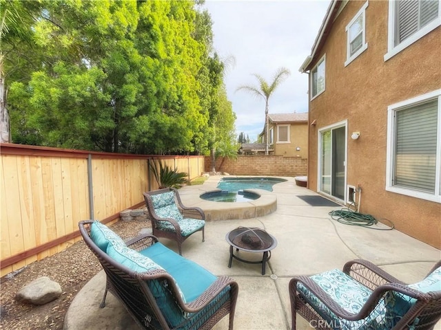 view of patio featuring an in-ground hot tub, an outdoor fire pit, and a fenced backyard