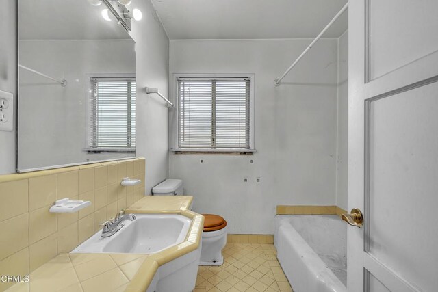 bathroom with tile patterned floors, toilet, a sink, a bathtub, and walk in shower