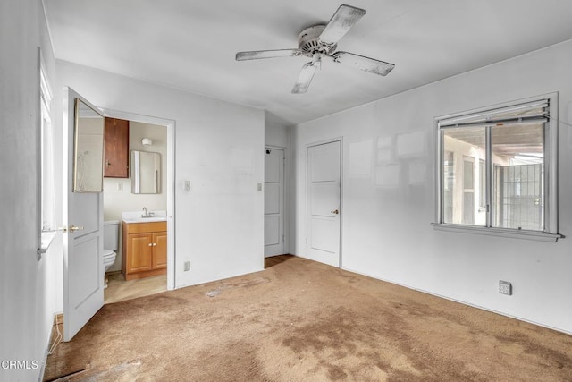 unfurnished bedroom featuring light carpet, a ceiling fan, a sink, and connected bathroom