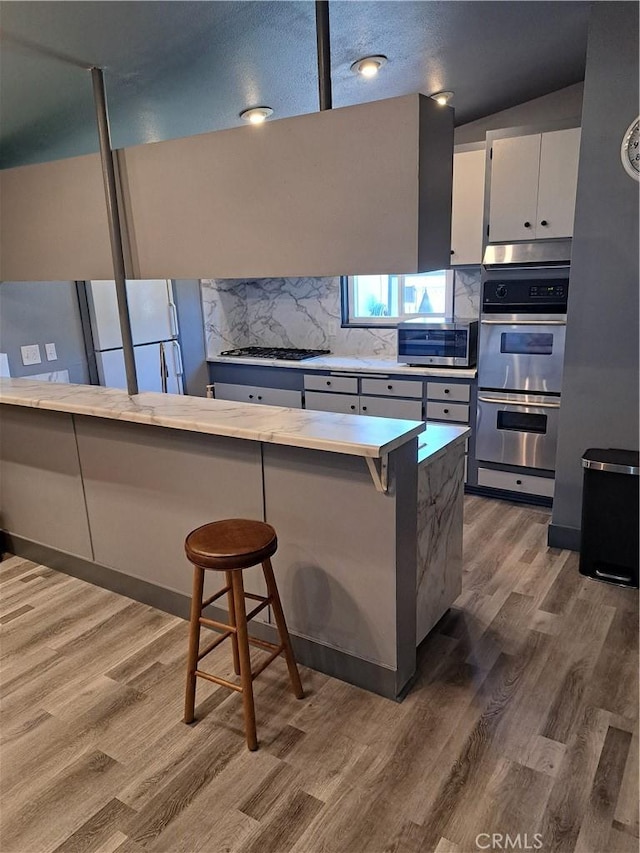 1230 Kilson Dr, Santa Ana, CA 92707 - kitchen with stainless steel appliances, wood finished floors, and tasteful backsplash