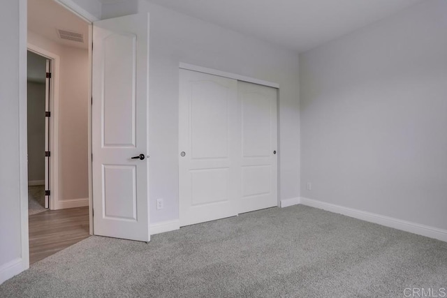 unfurnished bedroom with baseboards, visible vents, carpet, and a closet