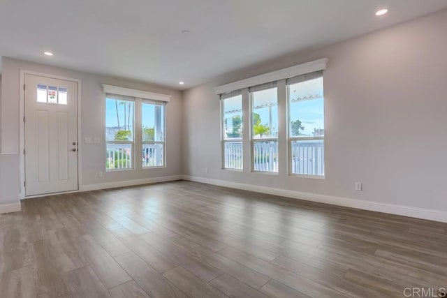 unfurnished living room with baseboards, wood finished floors, and recessed lighting