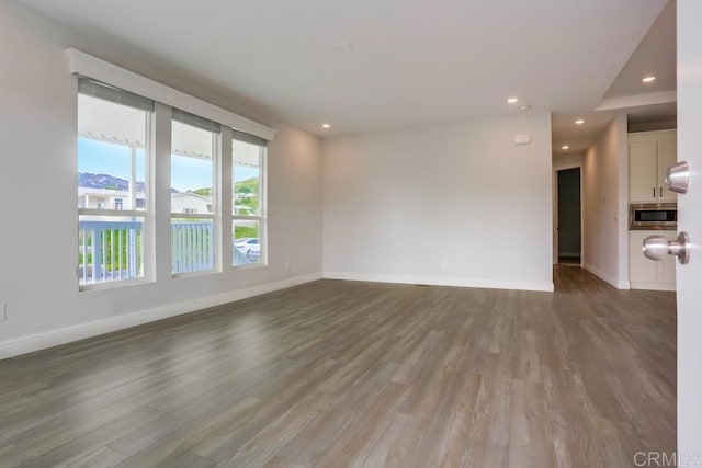 unfurnished living room featuring baseboards, wood finished floors, and recessed lighting