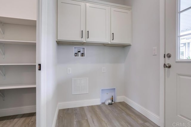 clothes washing area with visible vents, hookup for a washing machine, baseboards, cabinet space, and light wood-style flooring