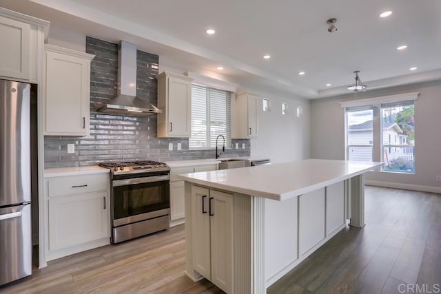 kitchen with a center island, a sink, light wood-type flooring, stainless steel appliances, and wall chimney exhaust hood