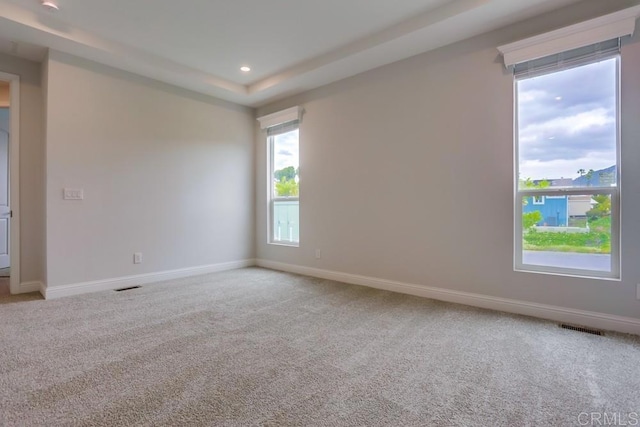 carpeted empty room with baseboards, a tray ceiling, visible vents, and recessed lighting