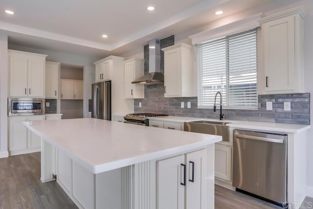 kitchen with wall chimney exhaust hood, a center island, a sink, tasteful backsplash, and appliances with stainless steel finishes