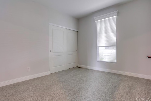 unfurnished room with light colored carpet and baseboards