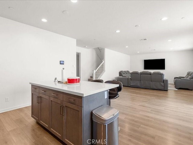 kitchen with recessed lighting, light countertops, a center island, light wood-style flooring, and open floor plan