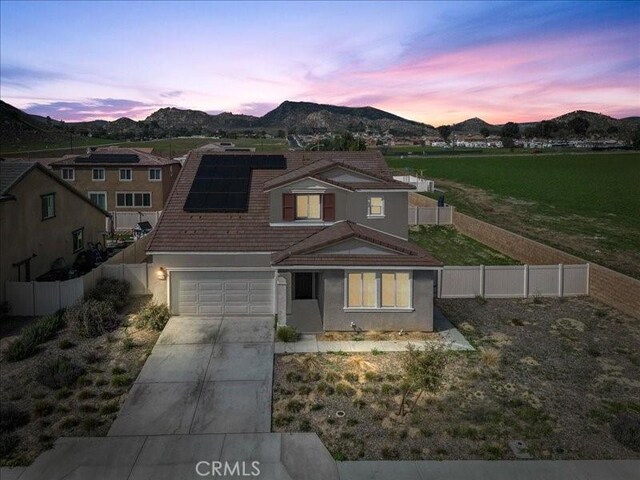 traditional home featuring a fenced backyard, a mountain view, solar panels, driveway, and a garage