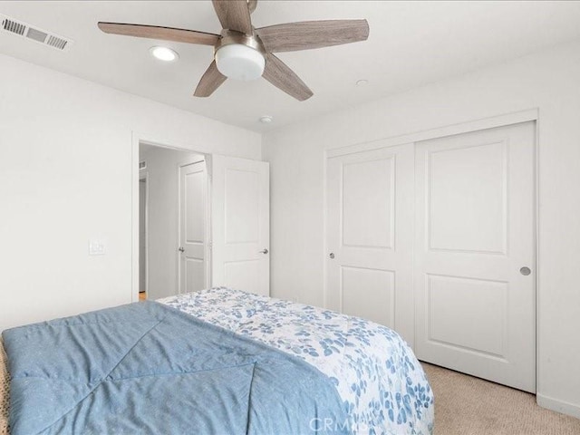 bedroom with recessed lighting, visible vents, a ceiling fan, a closet, and light colored carpet
