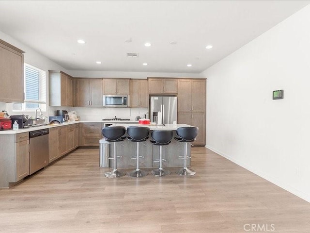 kitchen featuring recessed lighting, stainless steel appliances, a breakfast bar, and a kitchen island