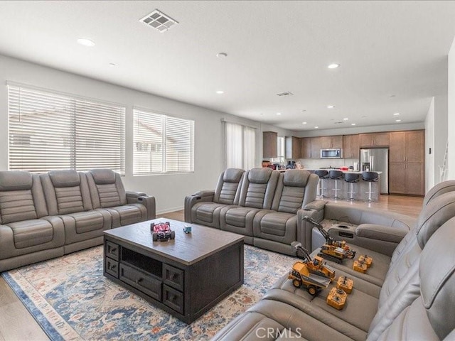 living area with baseboards, visible vents, recessed lighting, and light wood-style floors