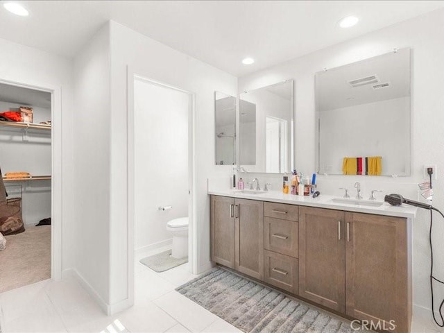 bathroom featuring recessed lighting, double vanity, toilet, and a sink