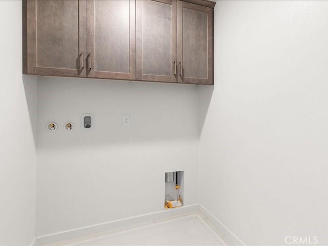 laundry area with hookup for an electric dryer, gas dryer hookup, hookup for a washing machine, baseboards, and cabinet space
