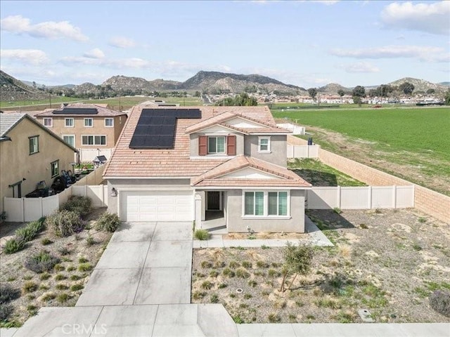 view of front of home featuring concrete driveway, a tiled roof, a fenced backyard, and stucco siding