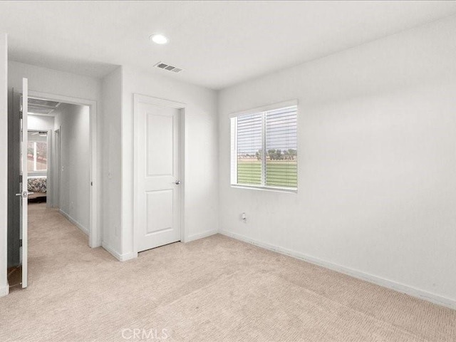 unfurnished bedroom featuring light carpet, baseboards, and visible vents