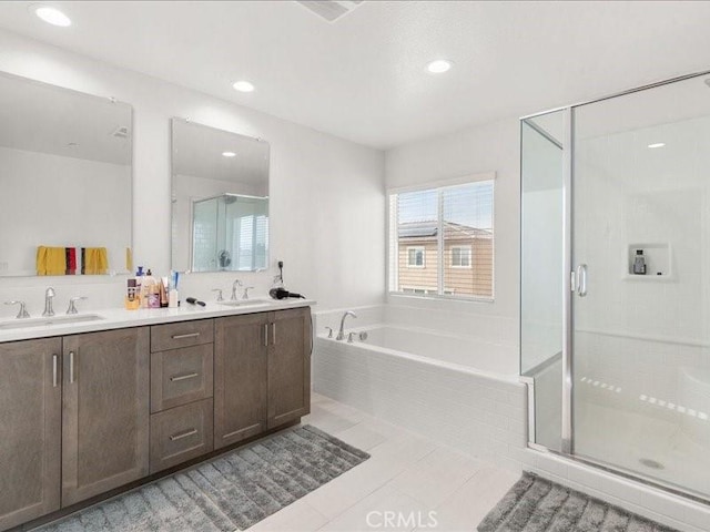 bathroom with double vanity, a shower stall, a garden tub, and a sink