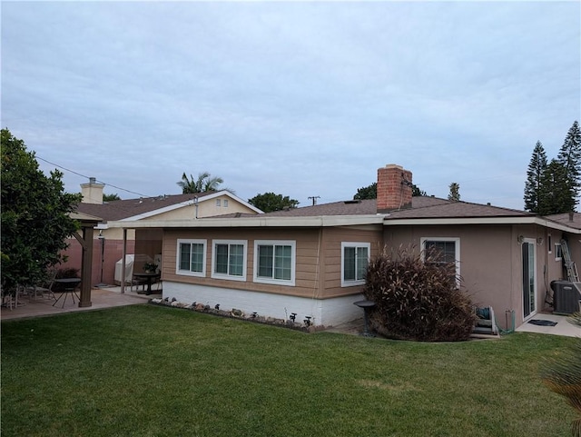 exterior space with a patio area, a chimney, a yard, and central air condition unit