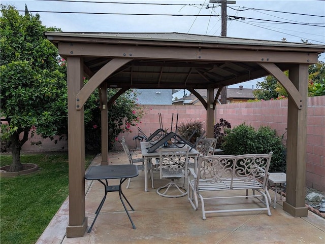 view of patio with a gazebo, outdoor dining space, and fence